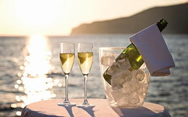 Champagne and glasses with a view towards the ocean from a cruise ship deck